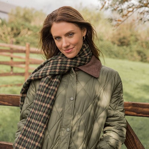 Woman wearing a green quilted jacket and plaid scarf outdoors