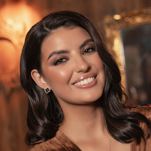 Woman with dark hair and a warm smile against a blurred background