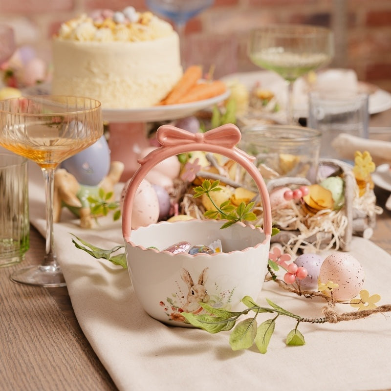 Decorative Easter basket with a bunny design on a table with pastel colors and Easter-themed items.