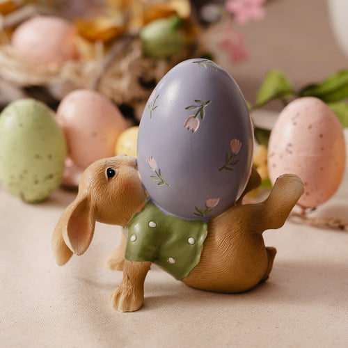 Decorative figurine of a rabbit with a painted Easter egg on its back, surrounded by colorful eggs and flowers.