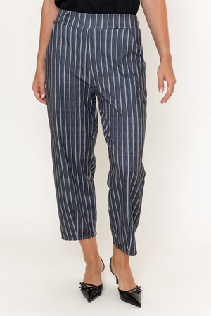 A model wearing navy blue cropped trousers with thin white vertical pinstripes, paired with black pointed-toe heels, shown from the waist down against a plain white studio background.