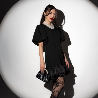 Women wearing a black min dress, holding a black clutch handbag