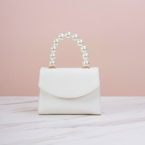 White handbag with pearl handle on a light pink background