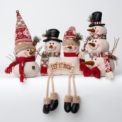 Four decorative snowman figurines arranged together on a white studio background. The snowmen are made of soft off-white fabric with red, green, and black holiday accents, including hats, scarves, bows, and one central sign that reads “LET IT SNOW.