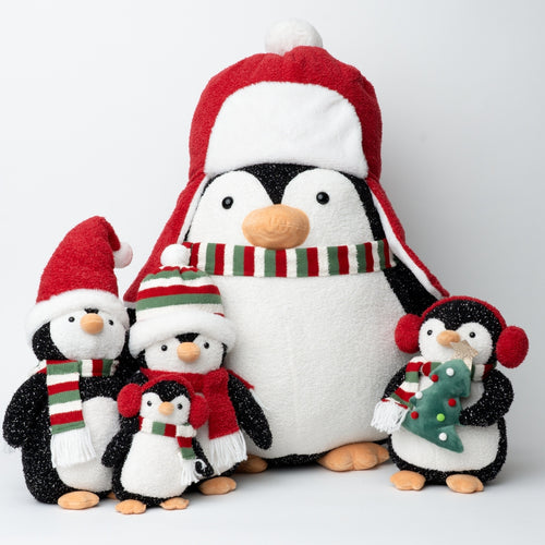 A set of plush penguin toys in different sizes, decorated with red and green holiday accessories including Santa hats, scarves, and earmuffs, on a light gray studio background.