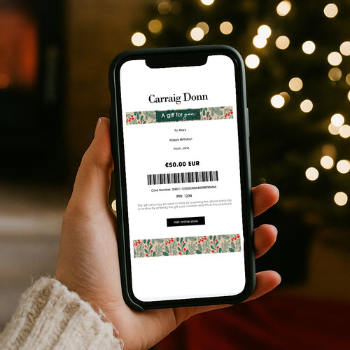 Hand holding a smartphone displaying a gift card on a blurred festive background
