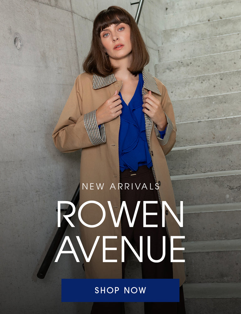 A woman wearing a beige Rowen Avenue trench coat over a bright blue blouse and dark trousers, standing on concrete stairs with large text overlay reading 'NEW ARRIVALS ROWEN AVENUE' and a blue 'SHOP NOW' button.
