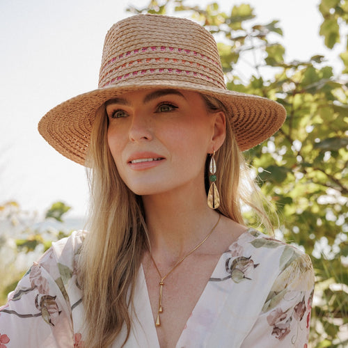 Woman wearing a straw hat with a floral pattern in an outdoor setting
